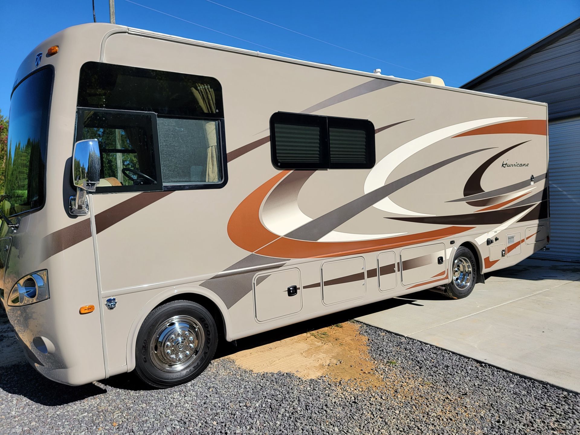 A large rv is parked in a driveway next to a garage.