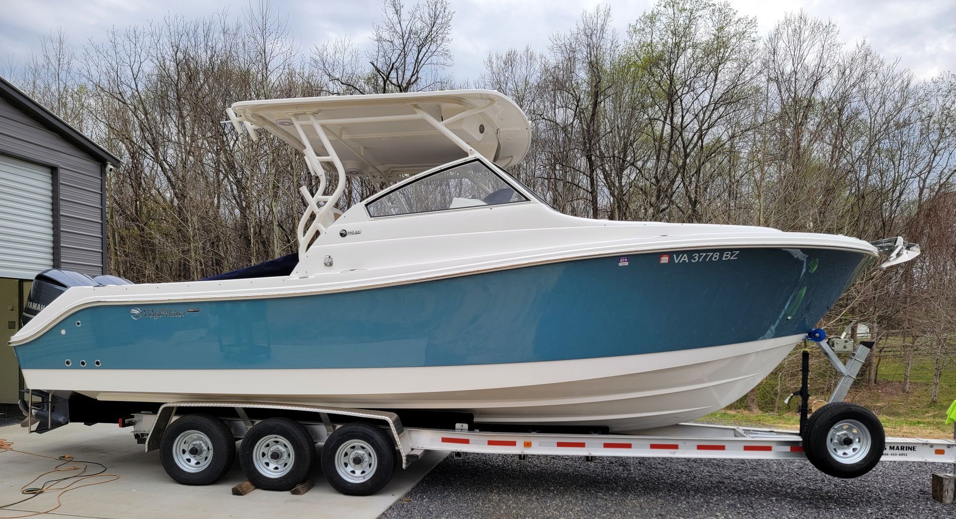 A blue and white boat is parked on a trailer.
