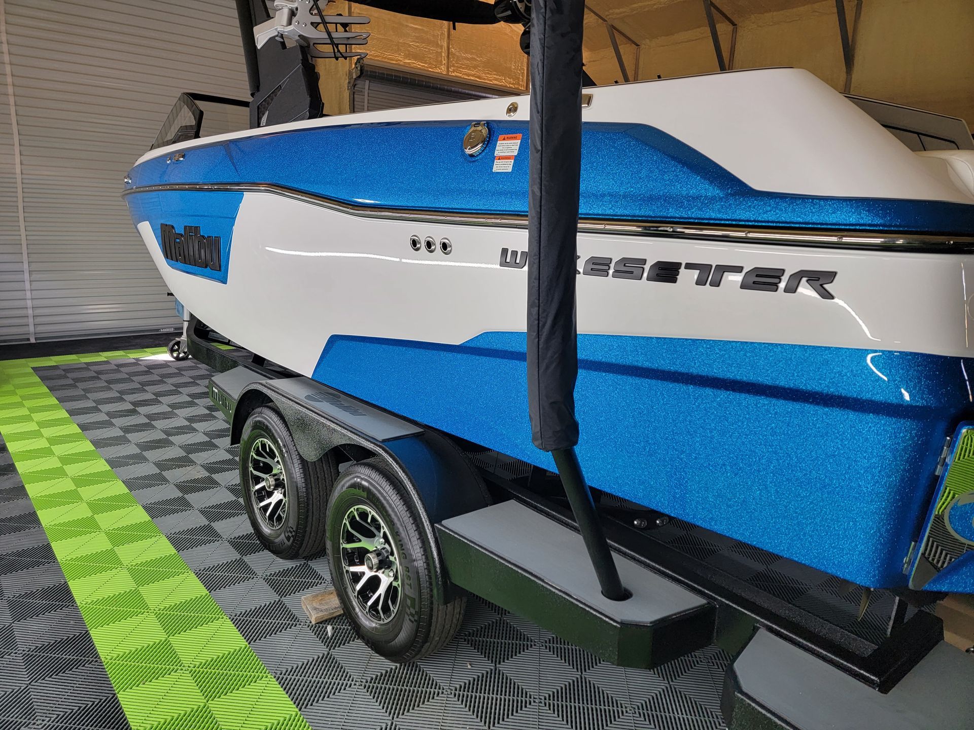 A blue and white boat is sitting on a trailer in a garage.