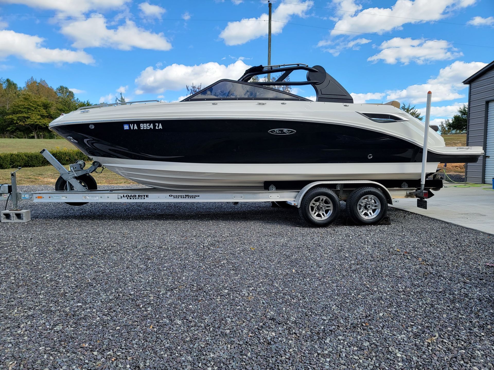 A boat is parked on a trailer in a gravel lot.