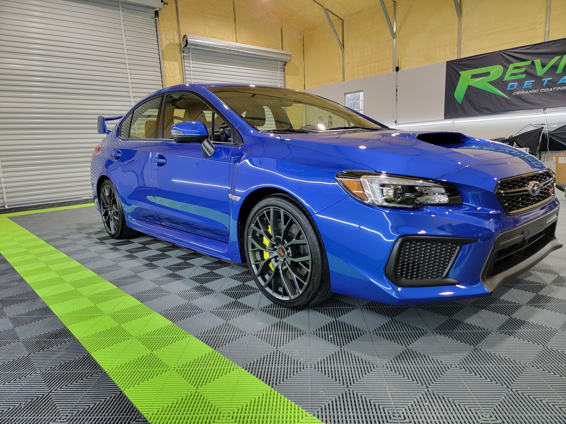 A blue subaru wrx sti is parked in a garage.