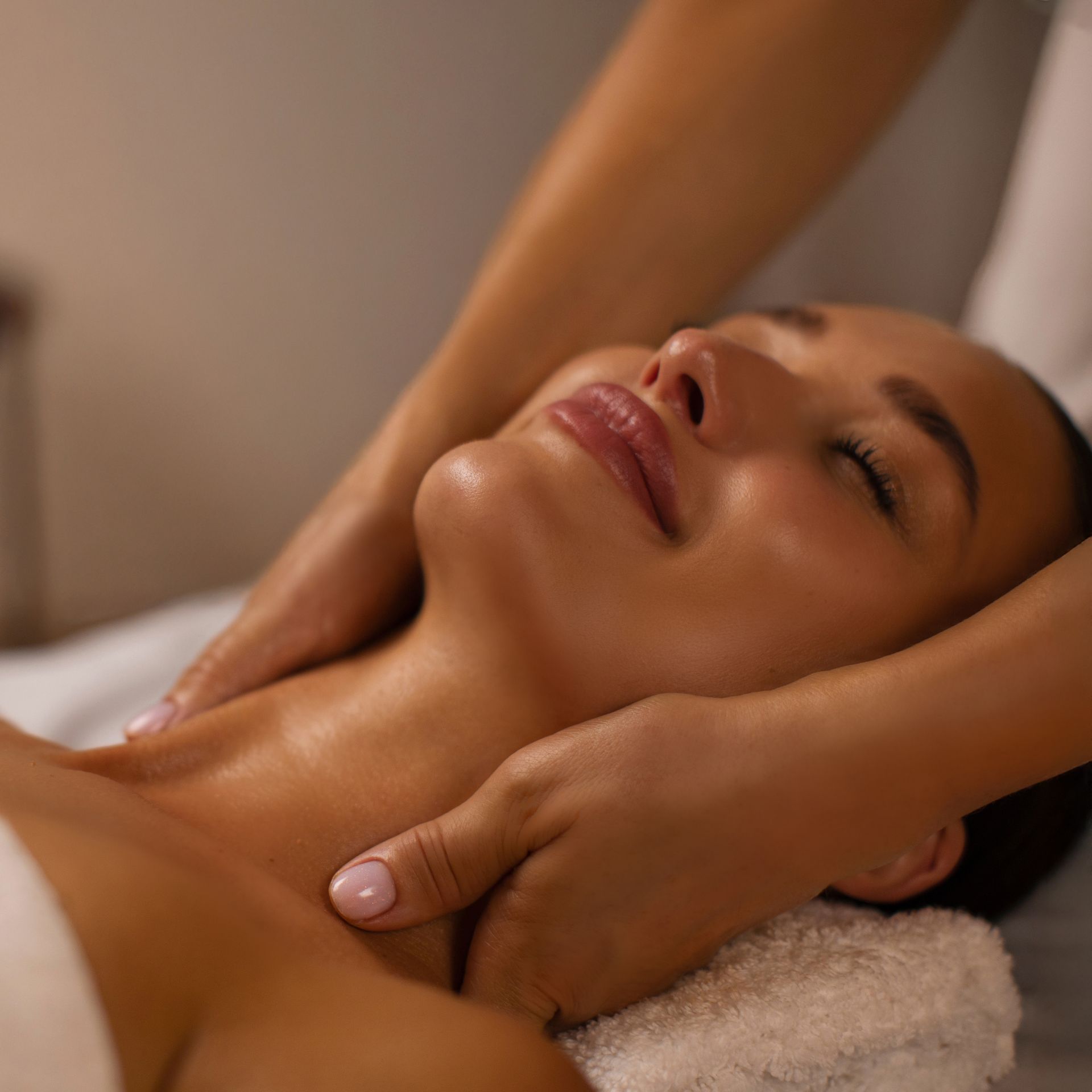 Woman receiving a neck massage, eyes closed, on a massage table.