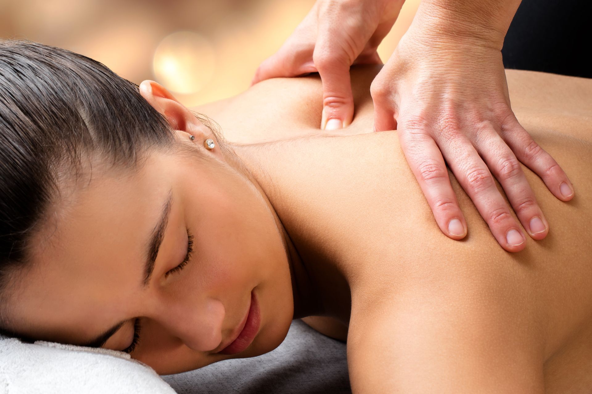 Hands giving a massage to a person lying face down.