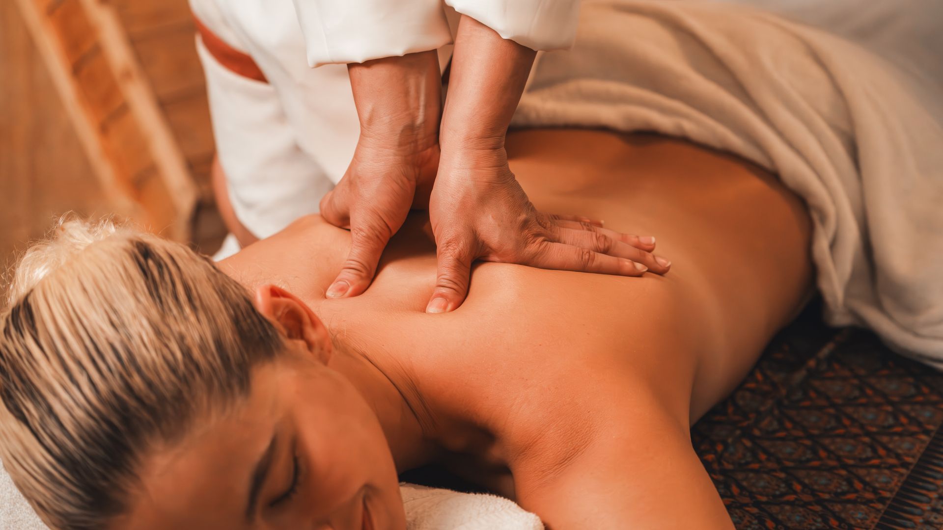 A person receiving a back massage at a spa; hands applying pressure.