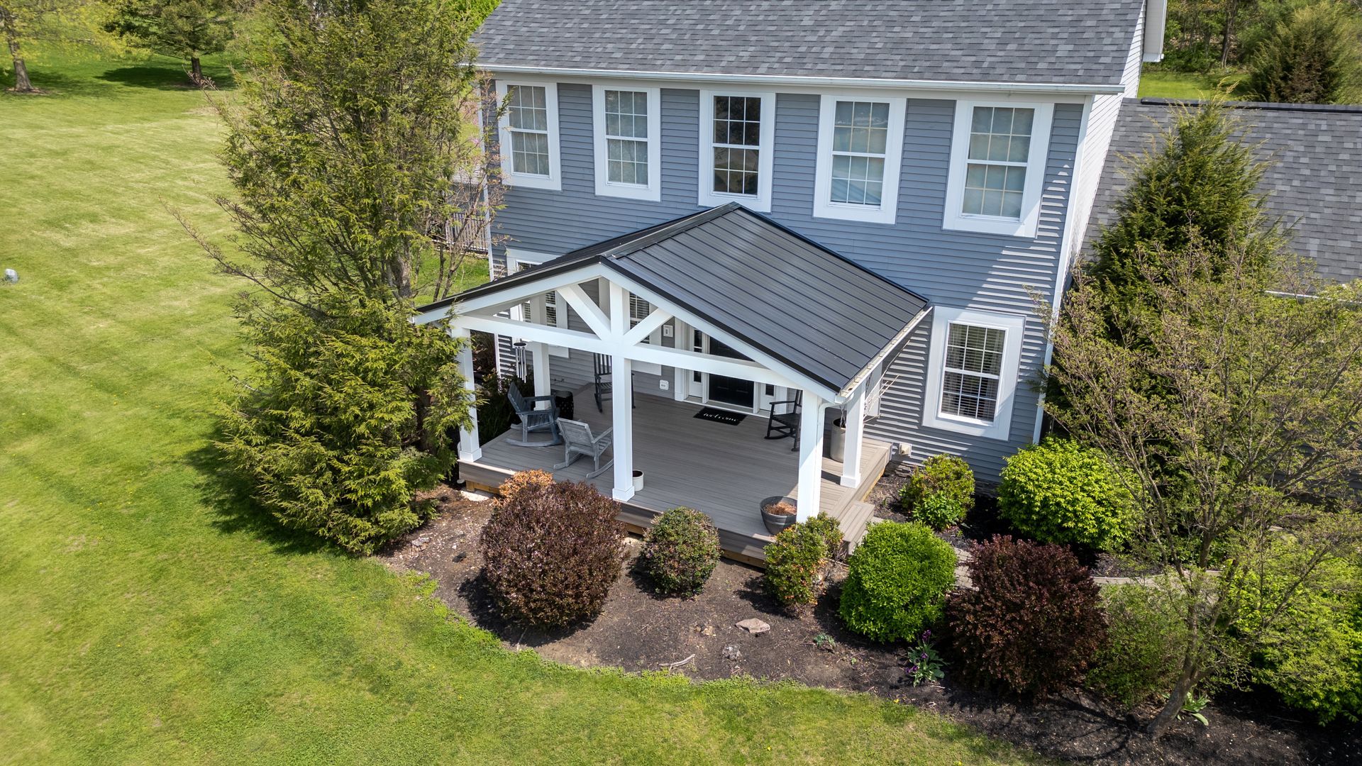 An aerial view of a house with a porch and a covered patio.