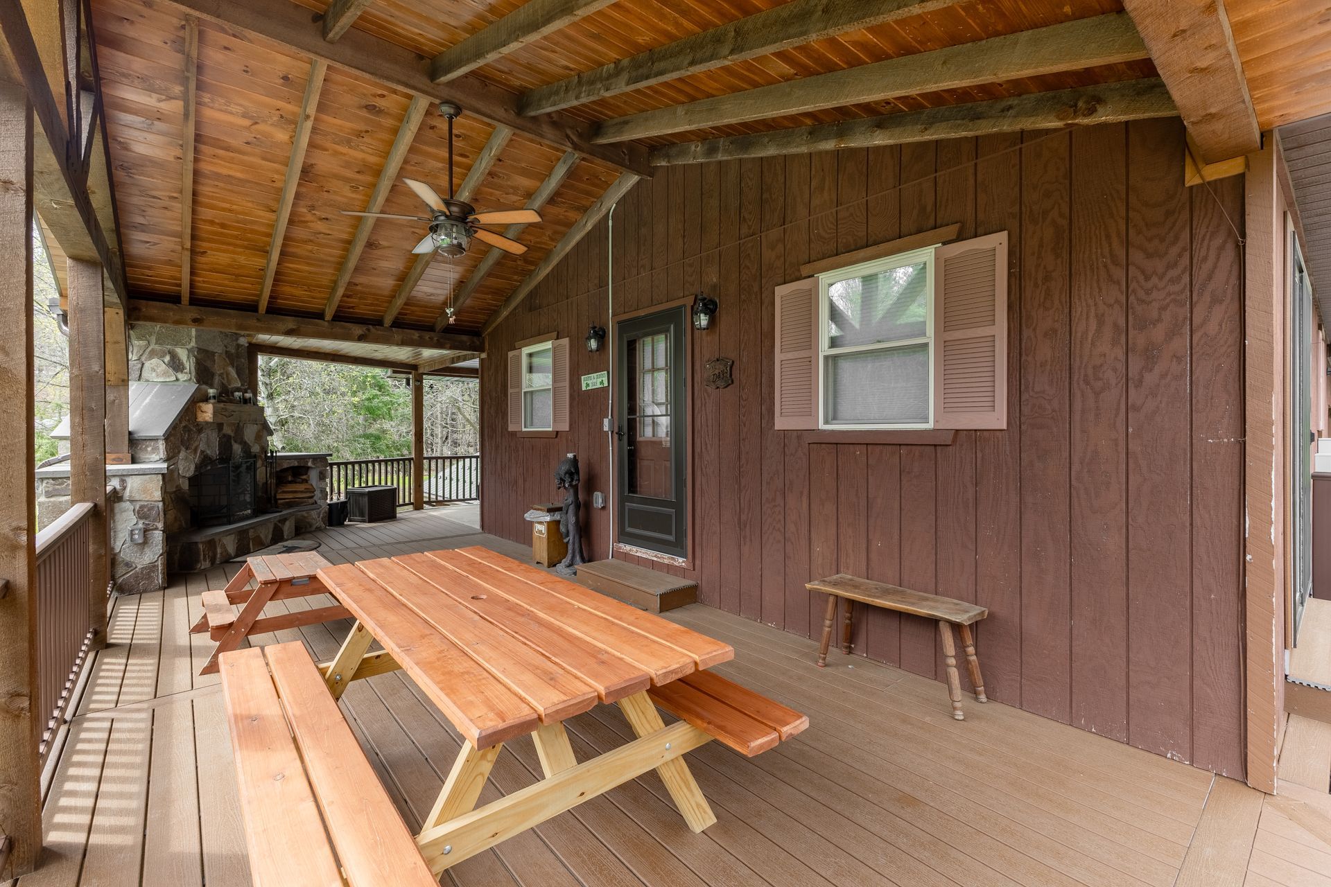 There is a picnic table on the porch of a cabin.