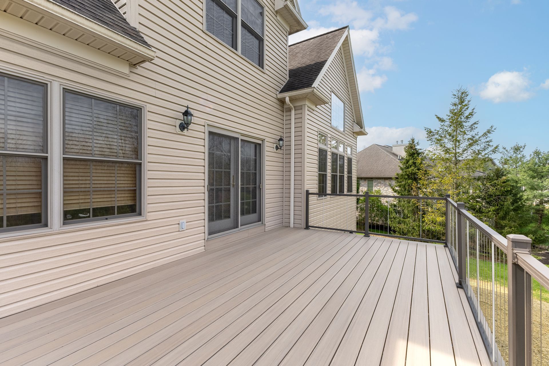 A large deck with a railing in front of a house.