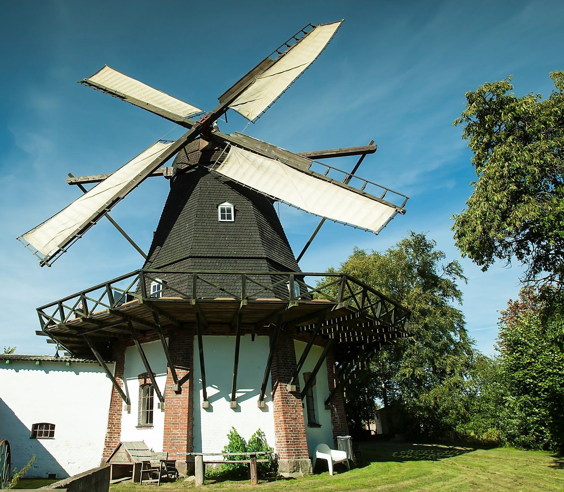 En stor vindmølle sidder foran en hvid bygning