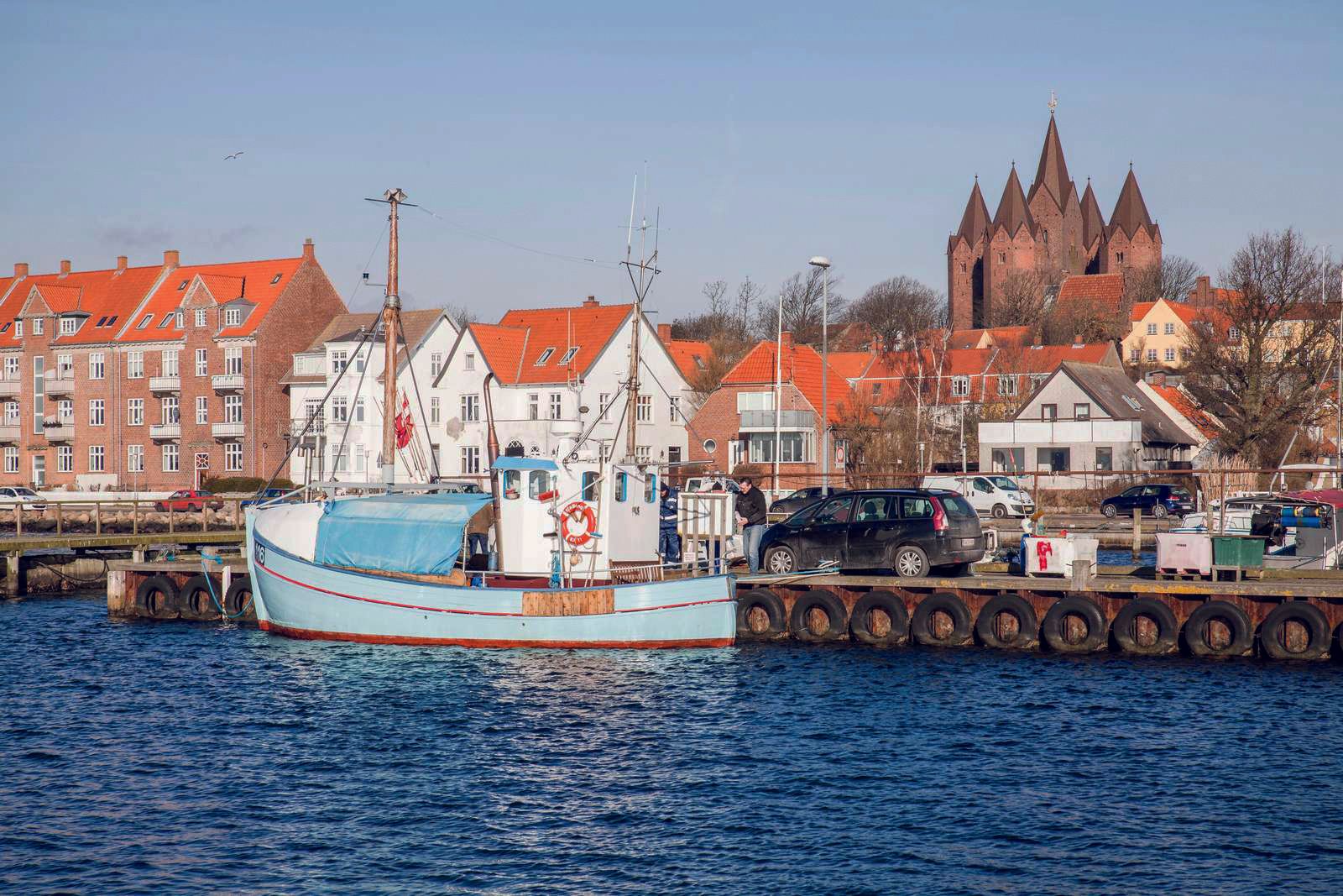 En båd ligger til kaj i vandet foran en by.