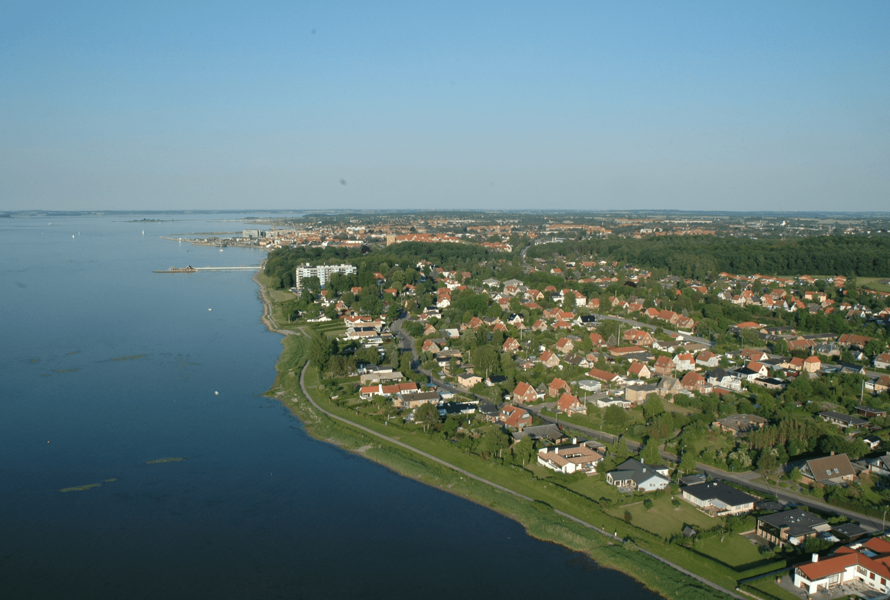 En luftfoto af en lille by ved siden af ​​en stor vandmasse.