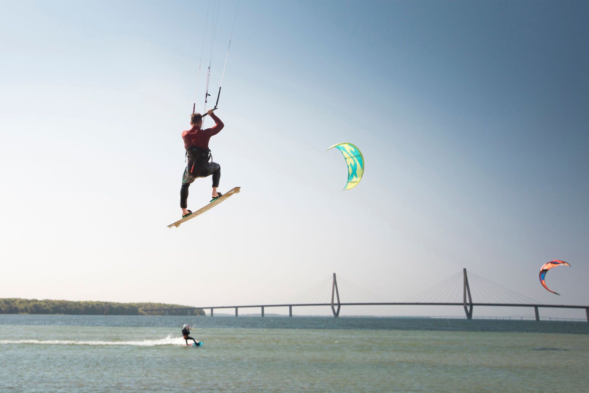 En mand flyver gennem luften, mens han kører på et surfbræt i vandet.