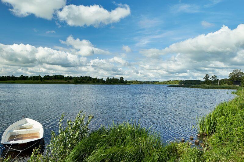 En båd sidder på bredden af ​​en sø på en solskinsdag.