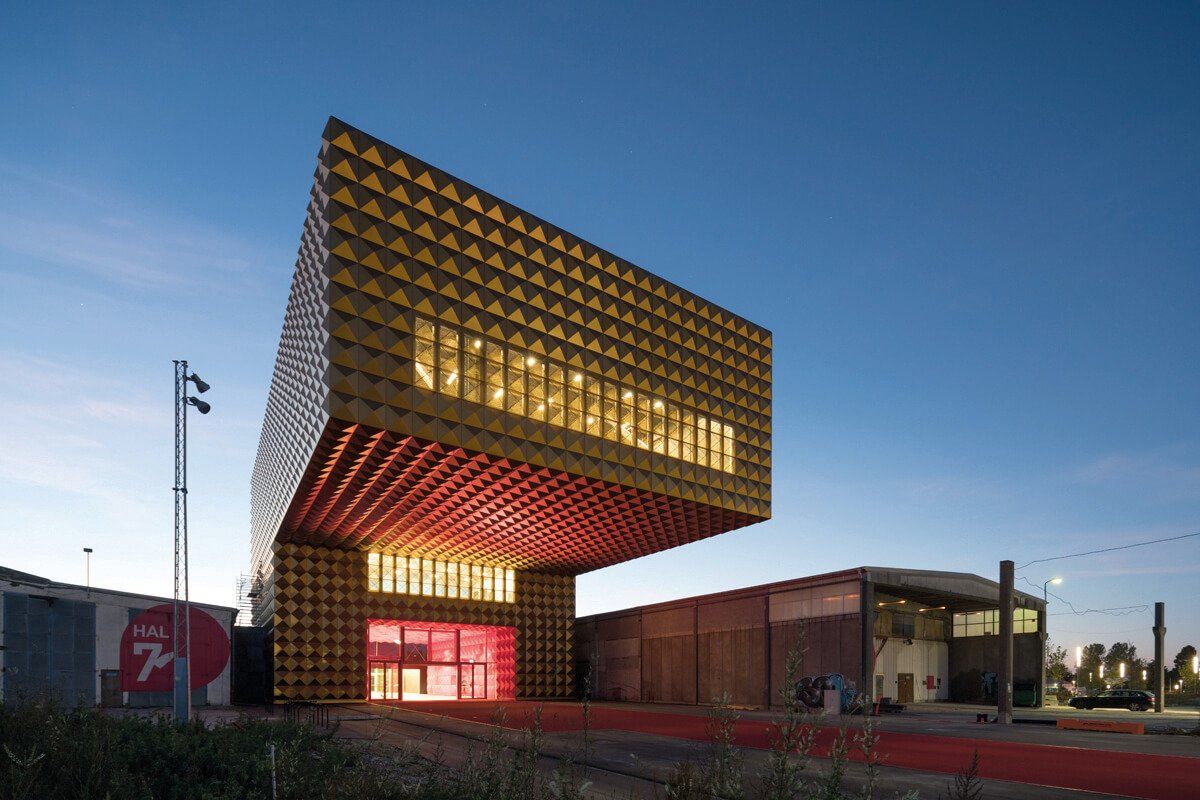 En stor bygning med mange vinduer lyser op om natten.