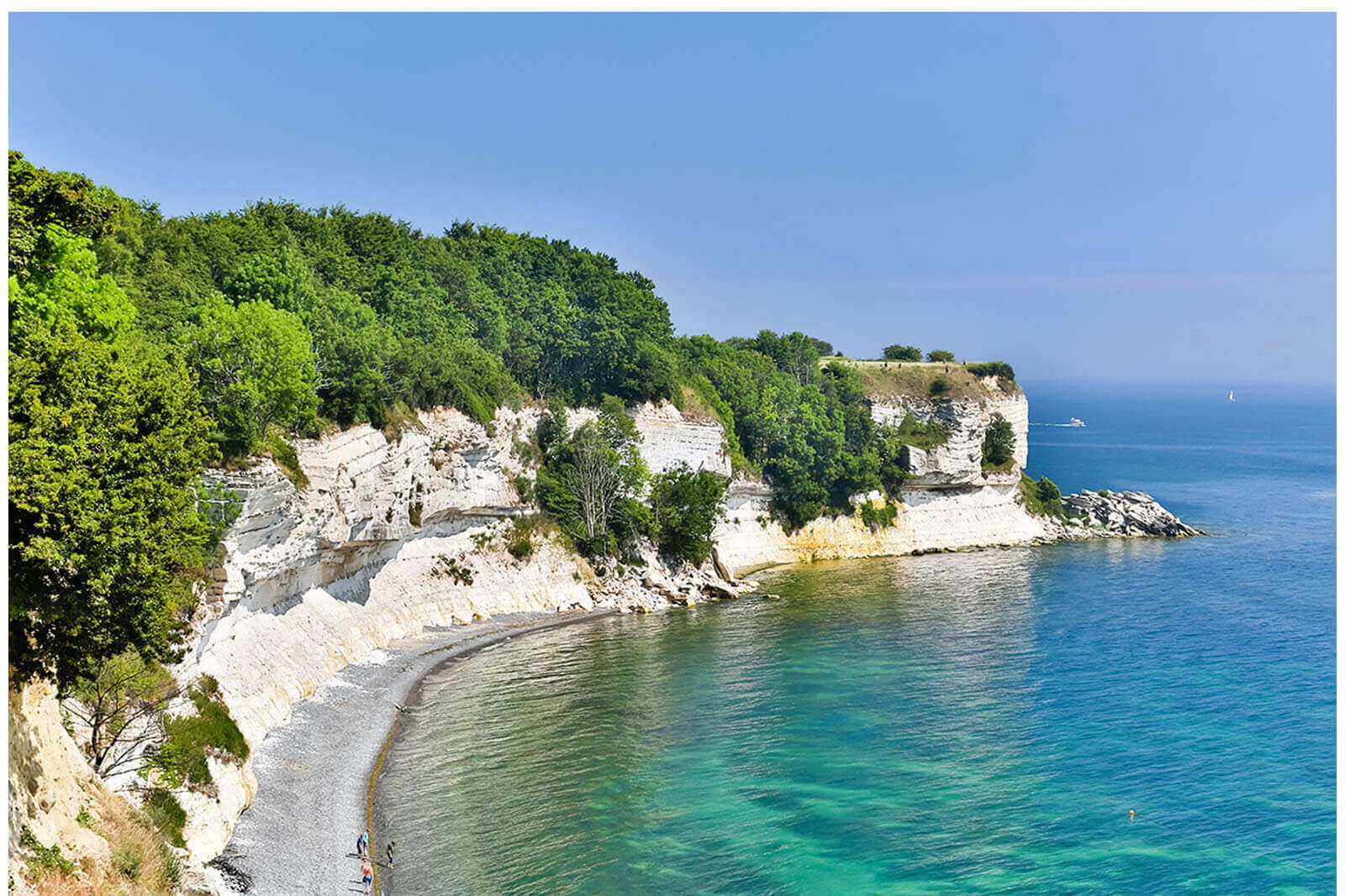 En klippe med udsigt over et vandområde med træer på.