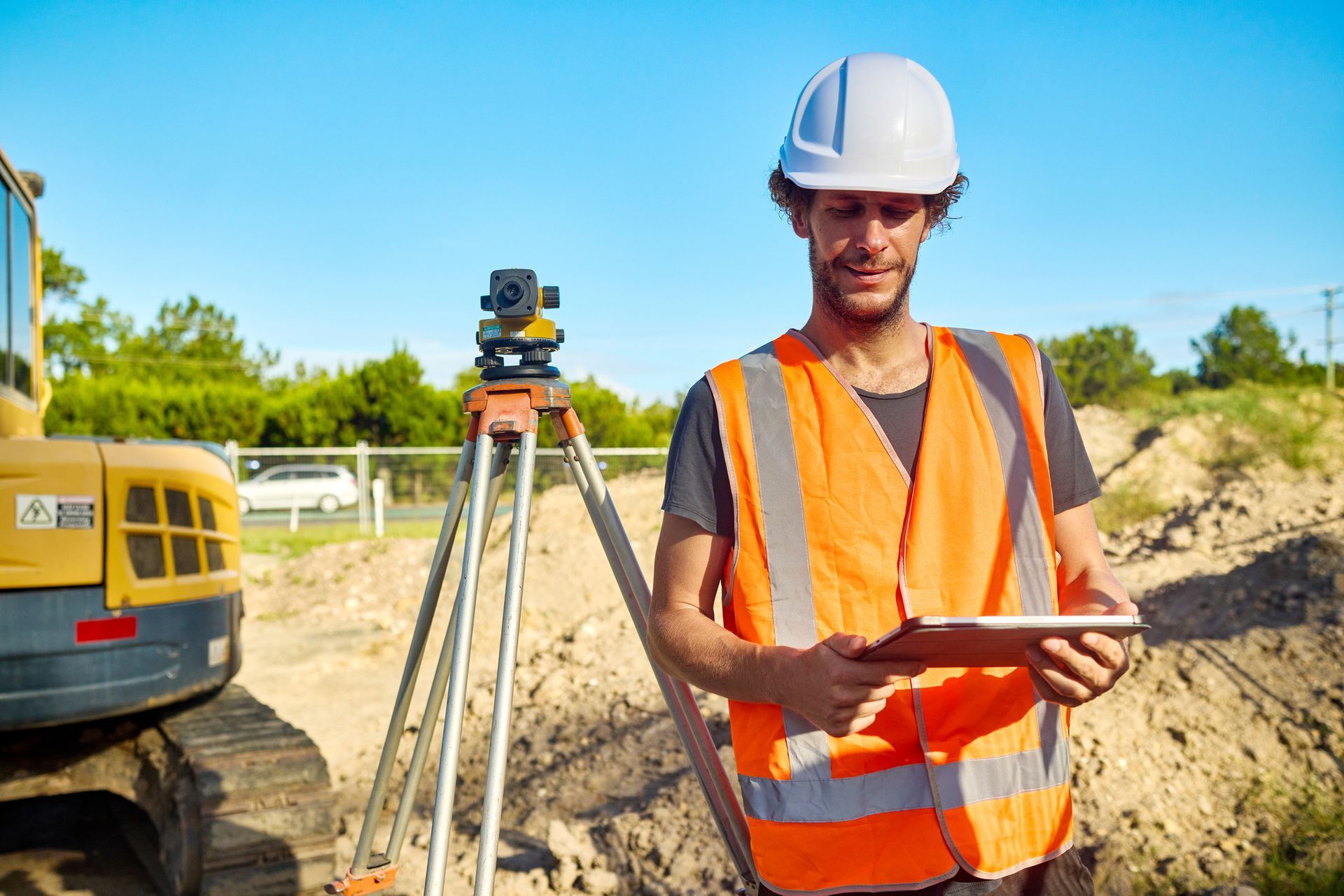 A surveyor is using a digital tablet next to a theodolite on a construction site. A surveyor is using a digital tablet next to a theodolite on a construction site.