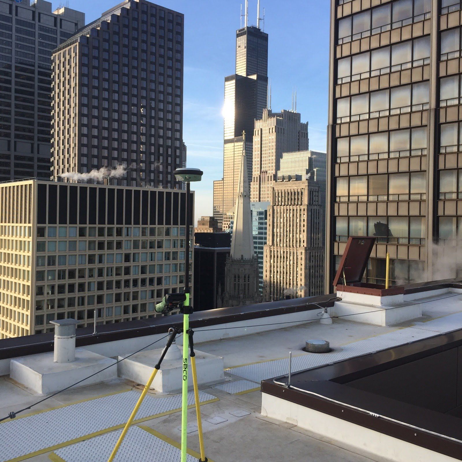A rooftop view of a city with a green tripod in the foreground