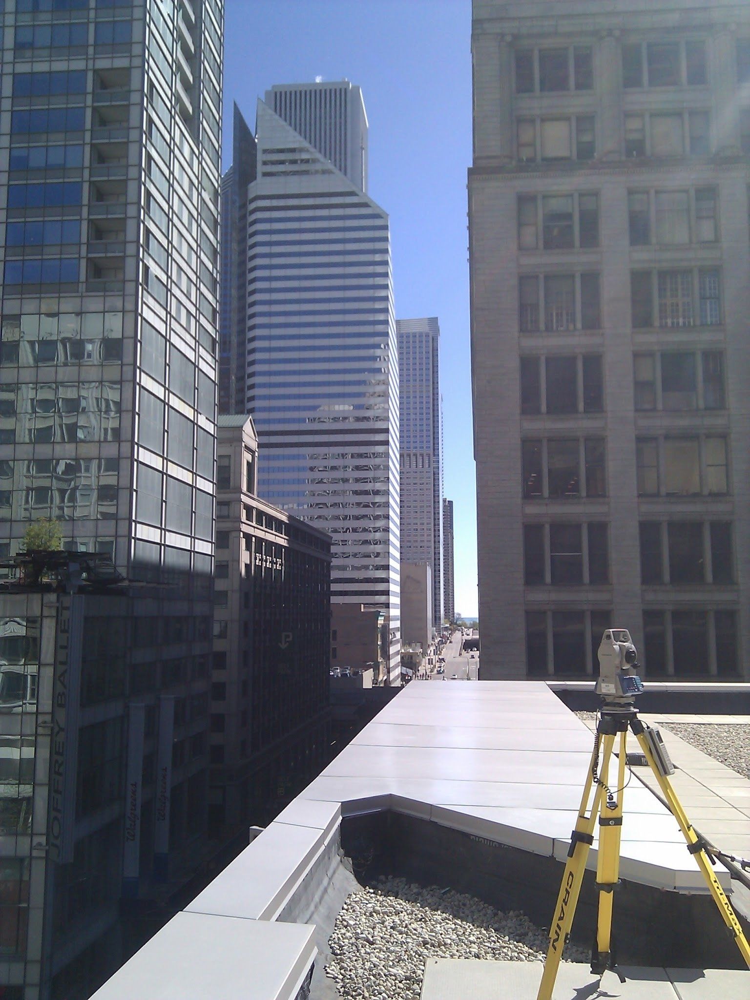 A tripod sits on top of a building in front of a city skyline