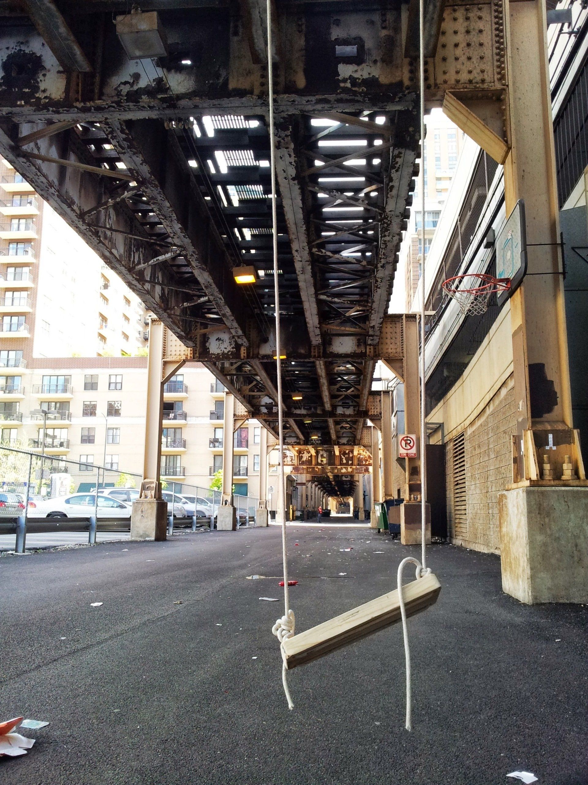 A swing is hanging from a rope under a bridge