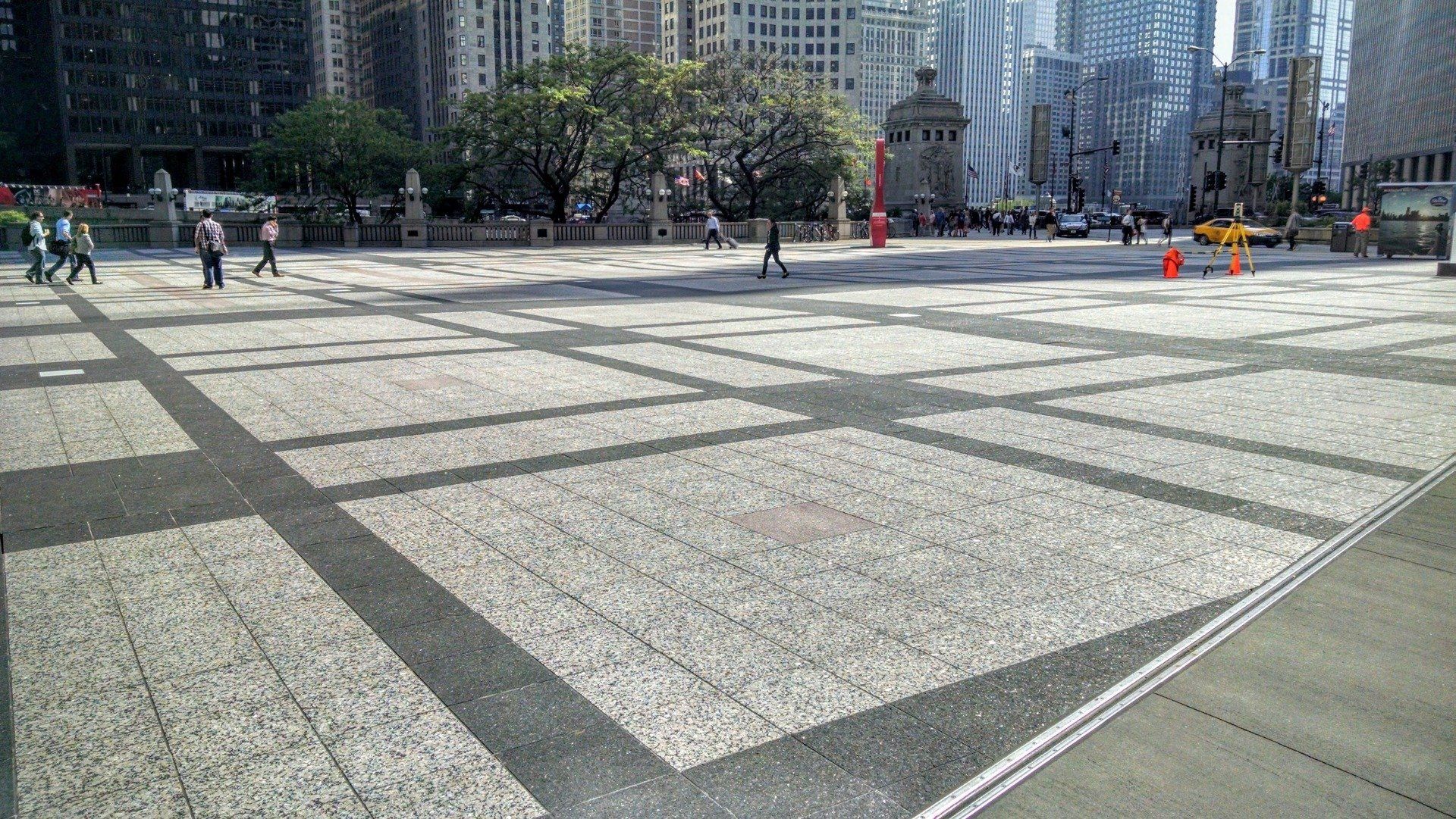 A large empty square in a city with people walking on it