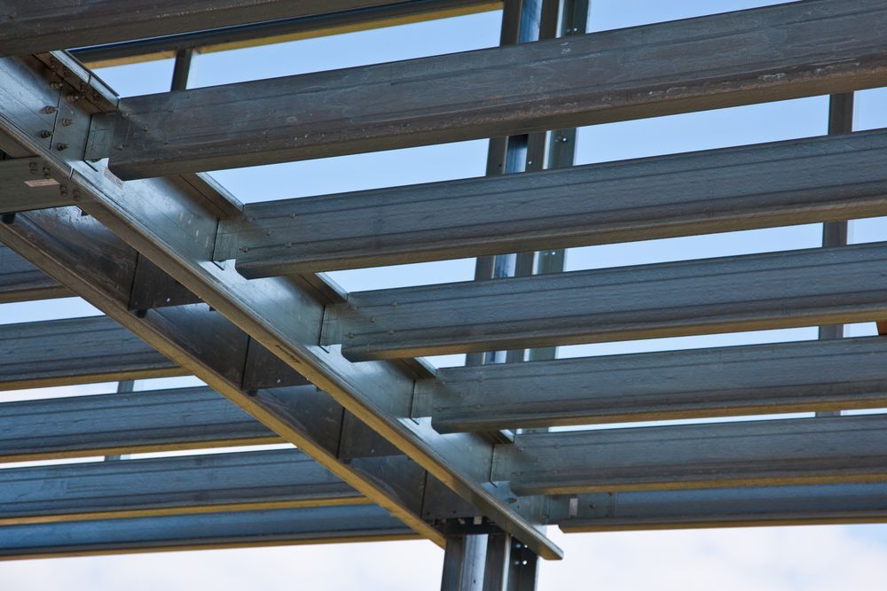 Close-up view of a steel roof frame structure under construction, featuring horizontal metal beams a