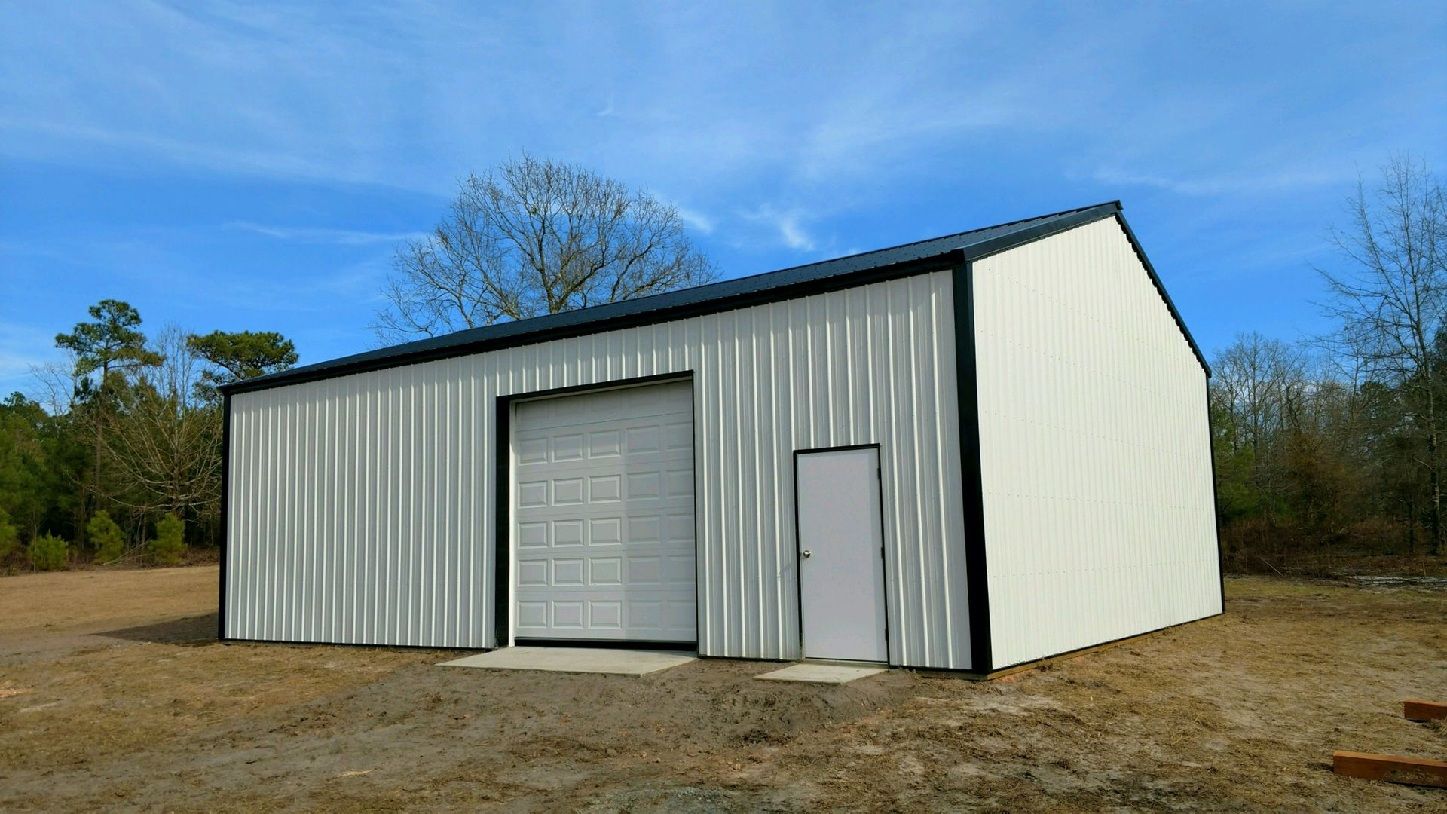 Small Gray Metal Shed With White Trim In A Grassy Field
