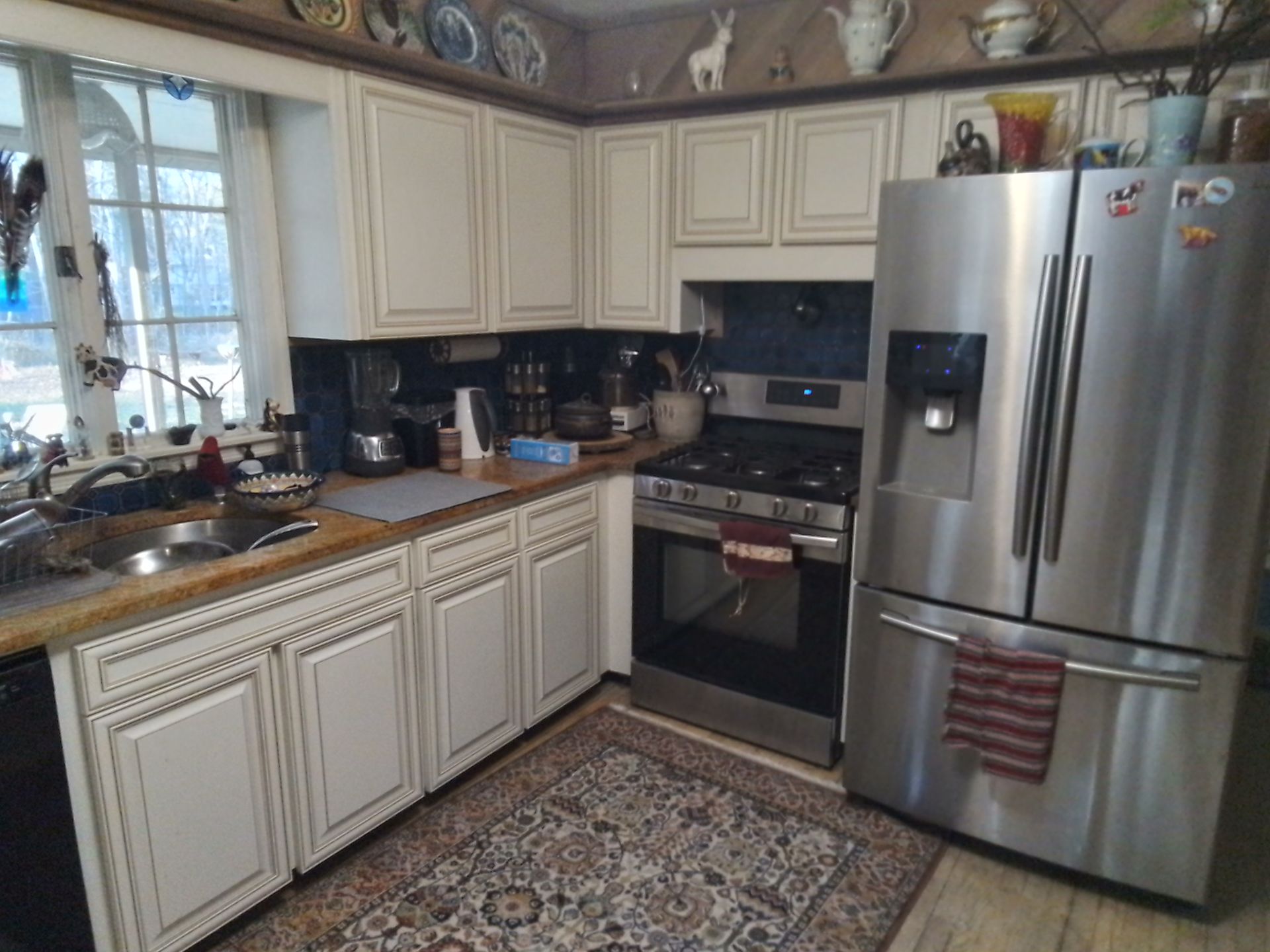 Cream kitchen with stainless steel appliances, wood countertops, and a patterned rug.