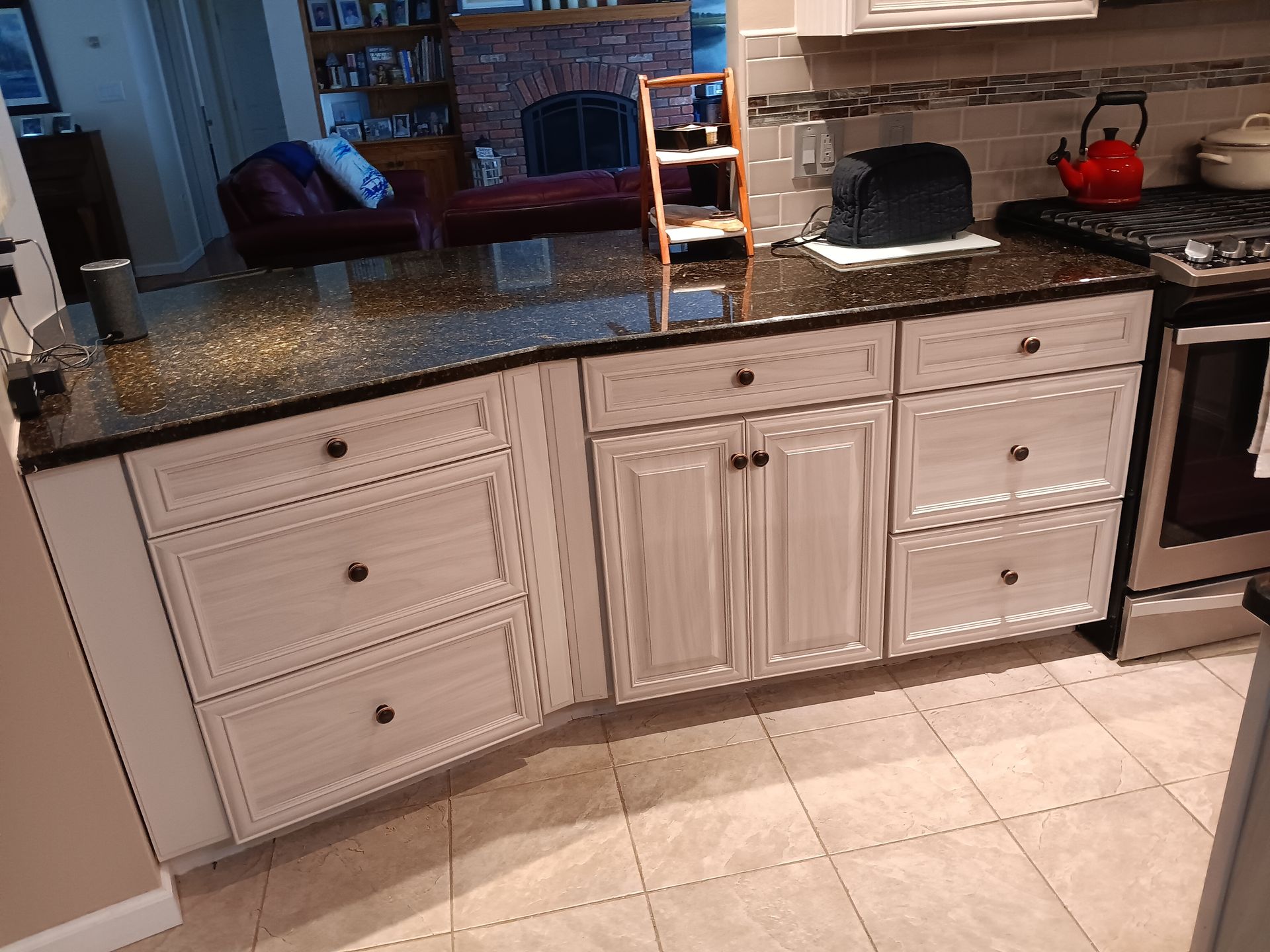 Kitchen with off-white cabinets, black countertop, and a stainless steel stove.