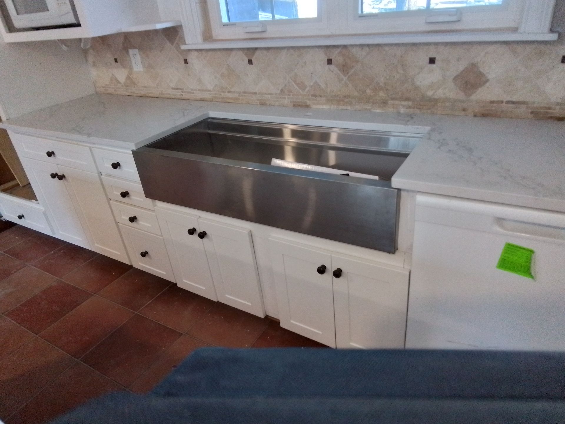 White kitchen cabinets with a stainless steel sink and light countertops.