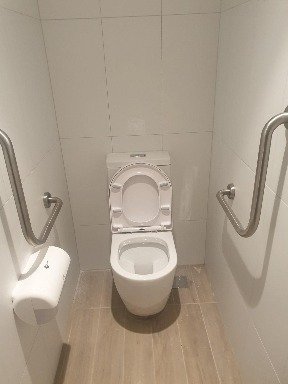 A Toilet in A Bathroom with Two Handrails on The Wall — Gillespie Plumbing in Grafton, NSW