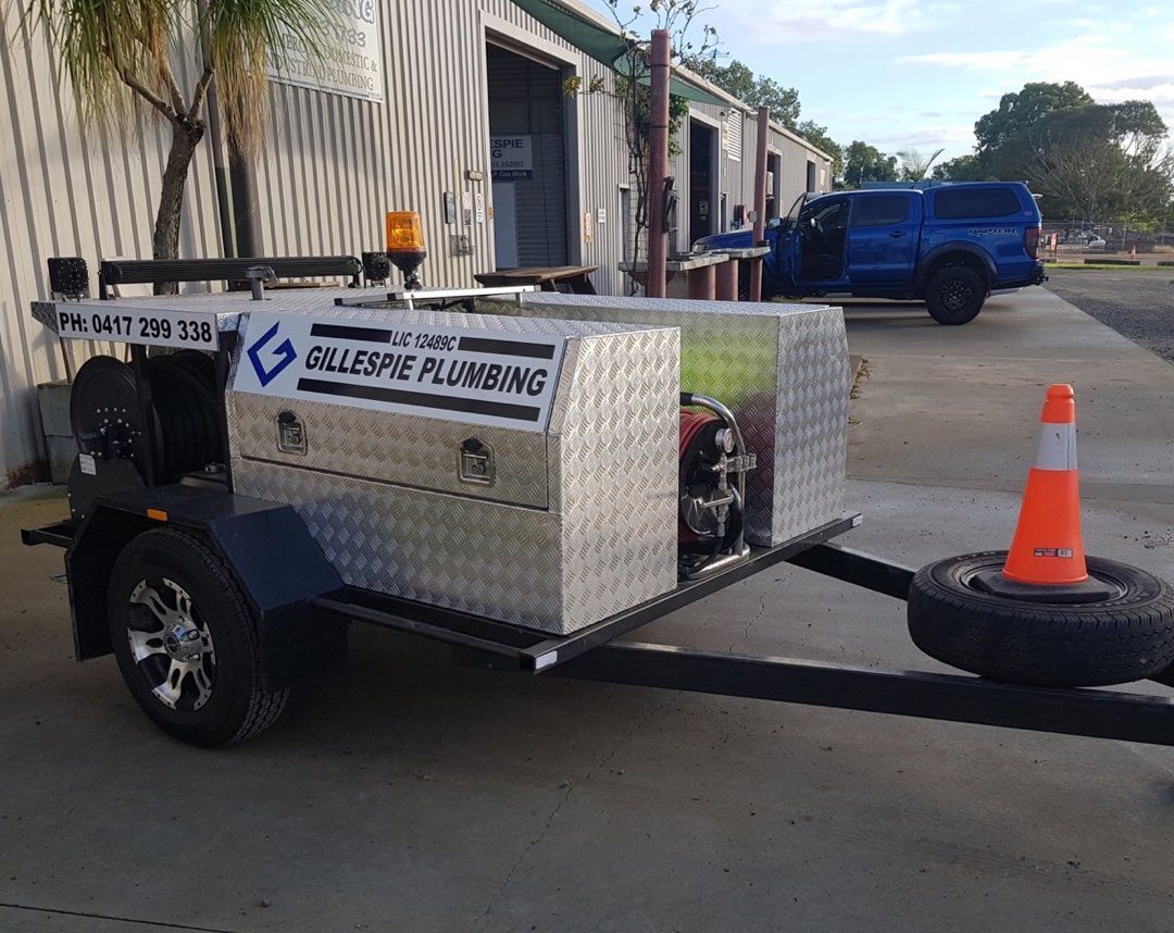 A Trailer with A Plumbing Company Logo on It Is Parked in Front of A Building — Gillespie Plumbing in Grafton, NSW