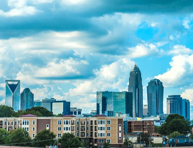 Charlotte, North Carolina skyline with tall buildings against a cloudy blue sky.