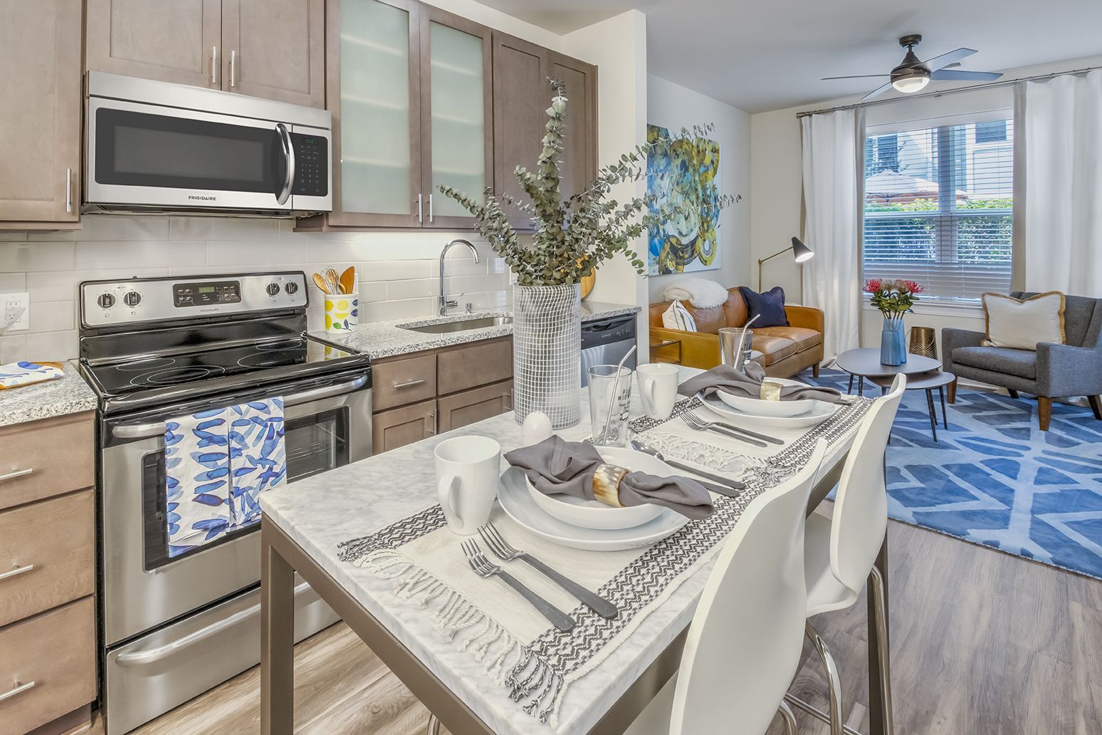 Modern kitchen and dining area with stainless steel appliances, granite countertops, and open to living room.