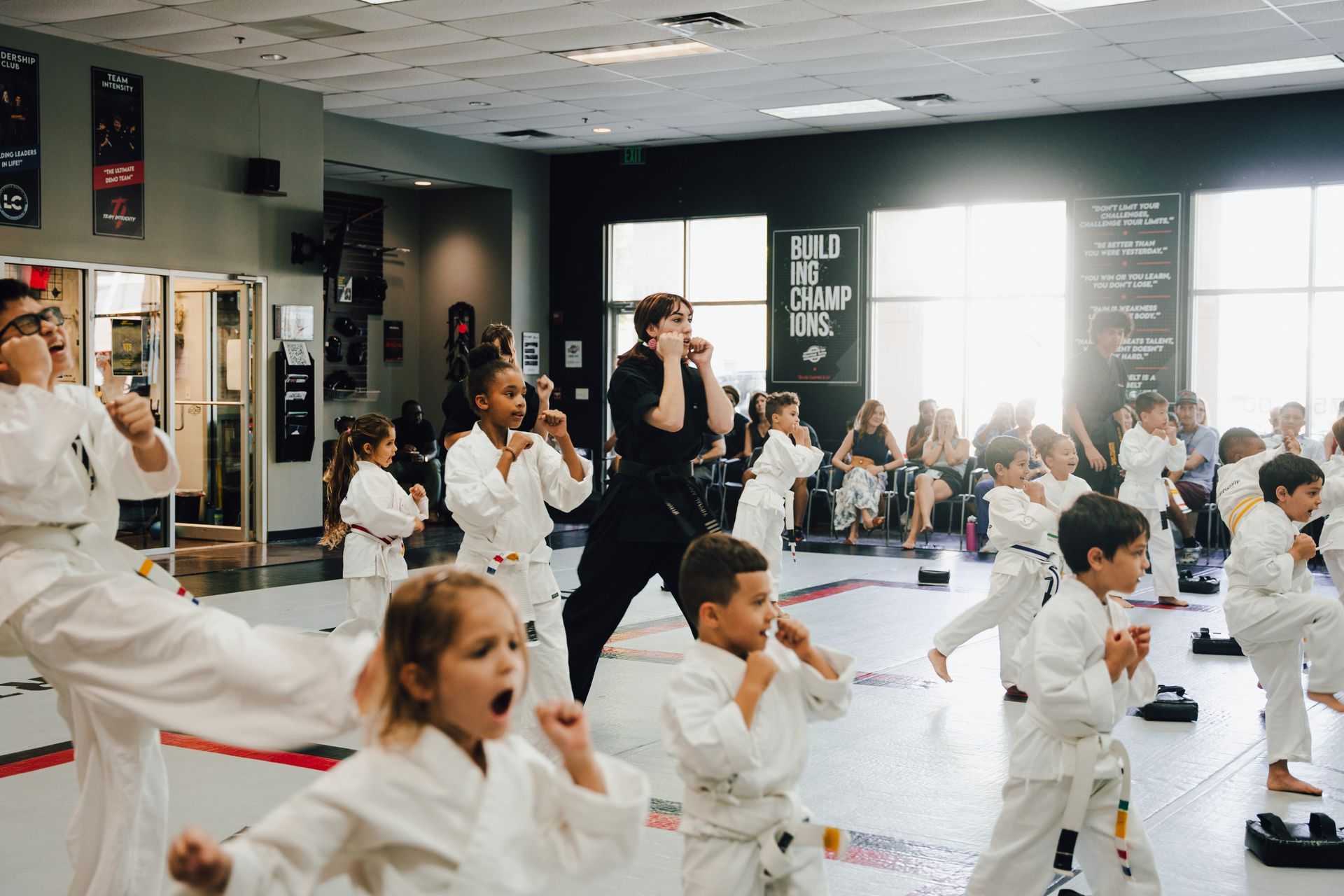 People in white martial arts uniforms stretching in a training room.