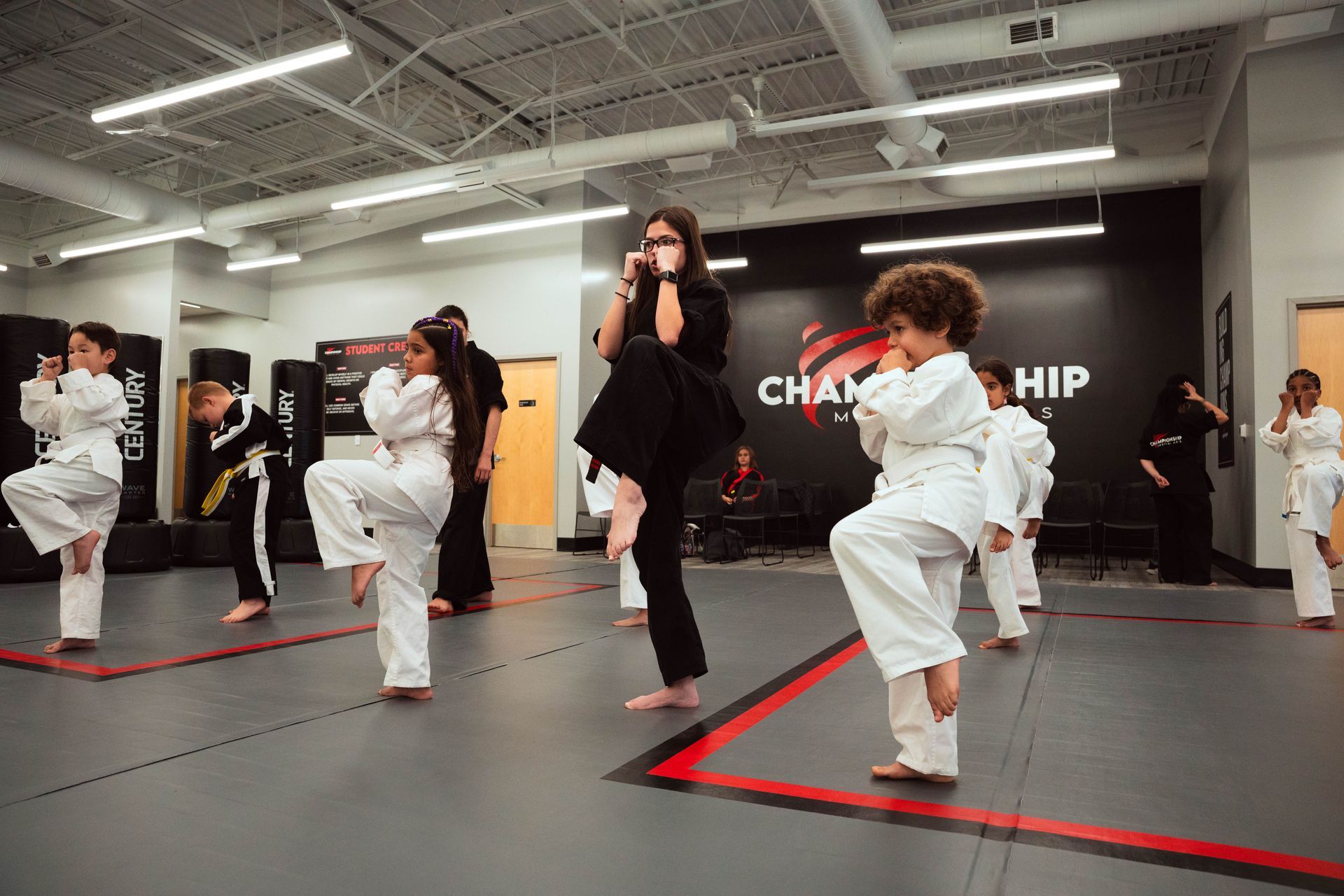 Two children in karate uniforms holding hands, outdoors, one with yellow belt, joyful expressions.