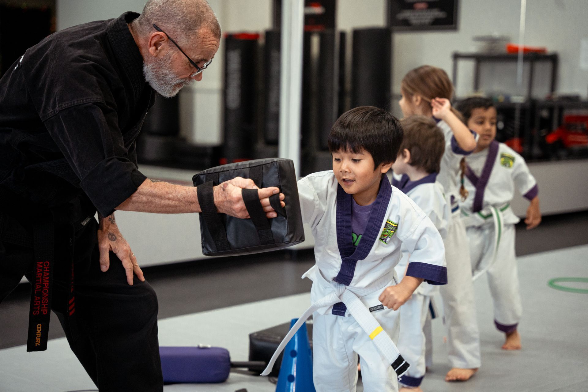 Four children in karate uniforms smiling, arms around each other.