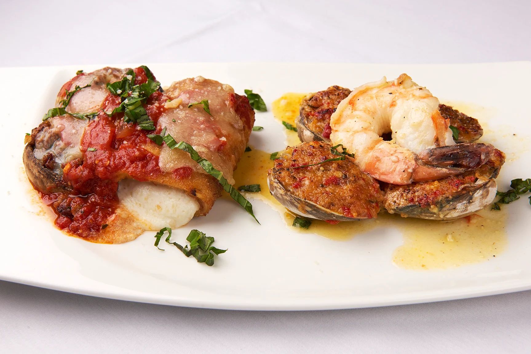 A white plate topped with two pieces of meat and shrimp