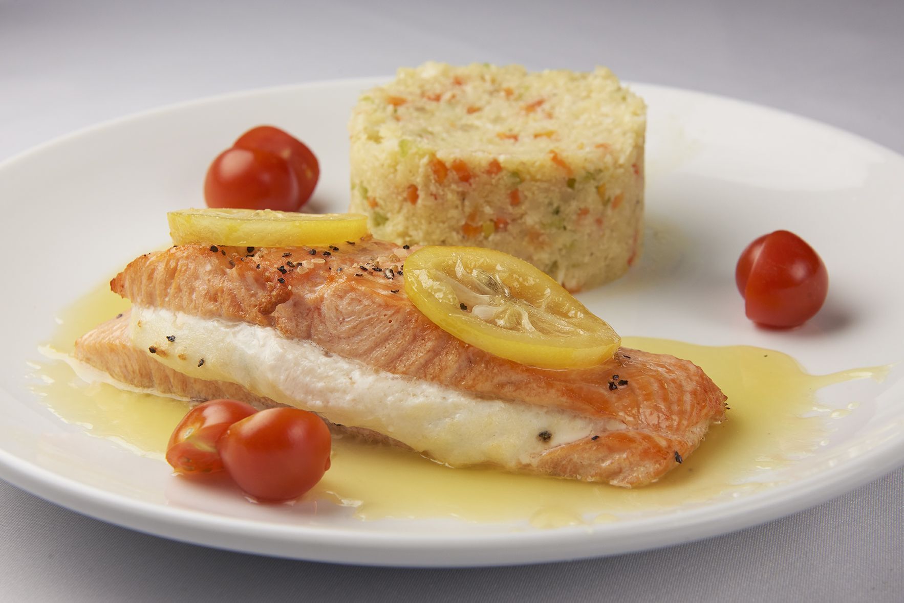 A white plate topped with salmon , rice and tomatoes.