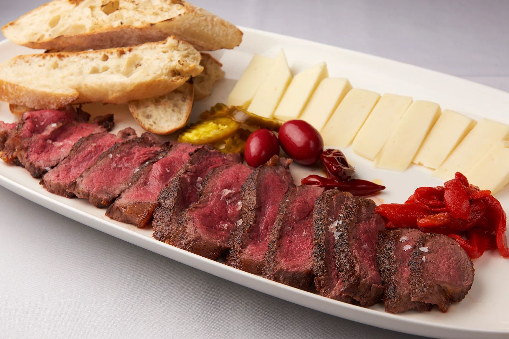 A white plate topped with meat cheese and bread