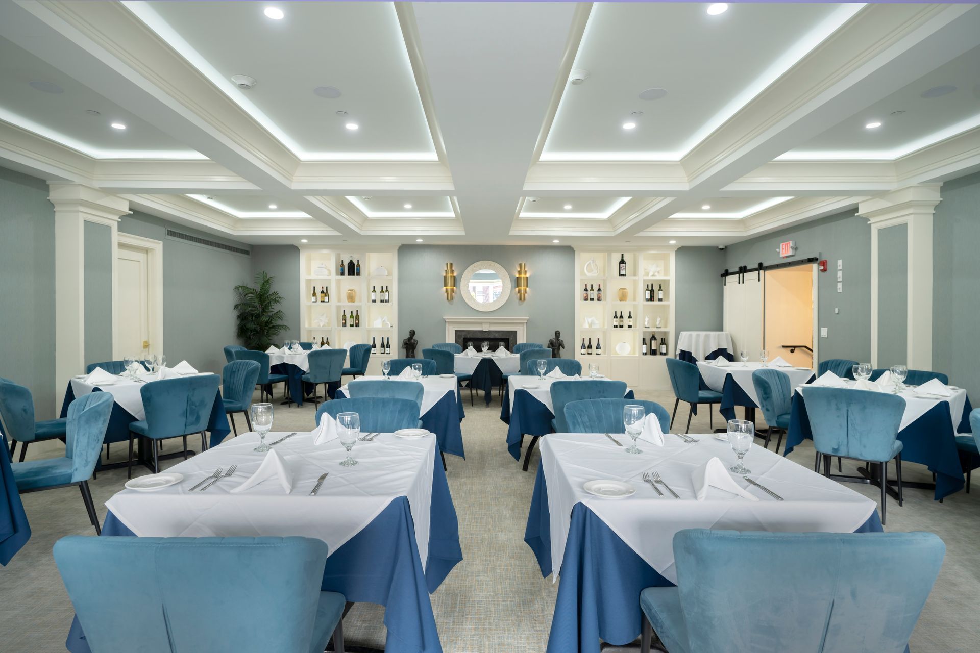 A large dining room with tables and chairs and a fireplace.