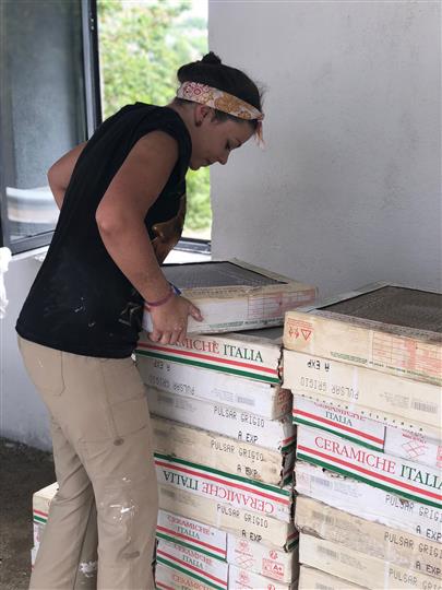 A woman is standing next to a stack of boxes that say ceramica italia