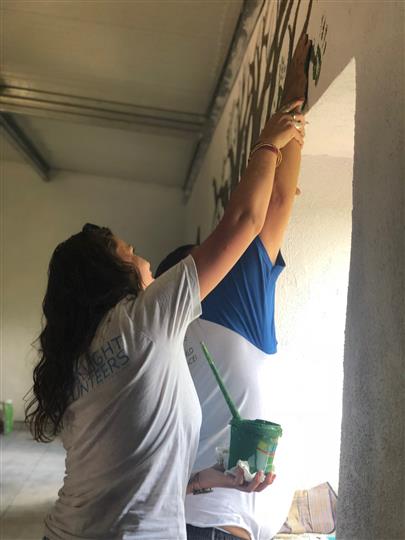 A man and a woman are painting a wall together