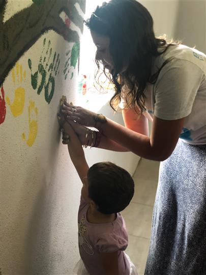 A woman and child are painting on a wall