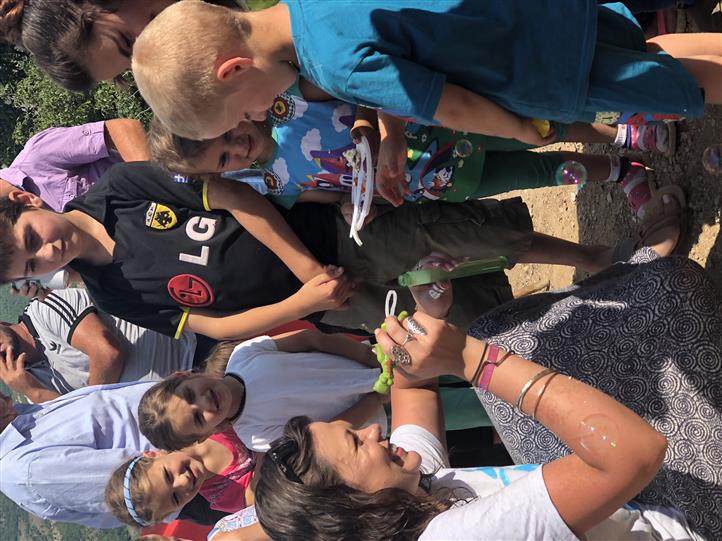 A group of children are playing with bubbles and one of them is wearing an lg shirt.