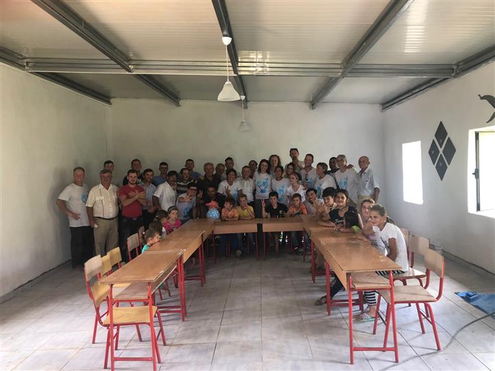 A group of people are posing for a picture in a room with tables and chairs.