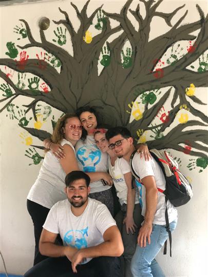 A group of people posing for a picture in front of a tree mural