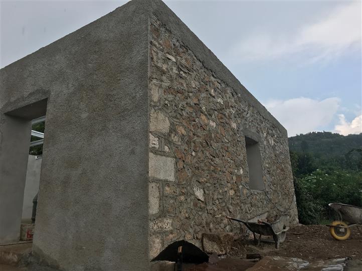 A stone wall with a concrete wall behind it