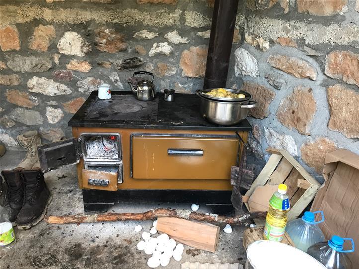 A stove with a pot on top of it in front of a stone wall.