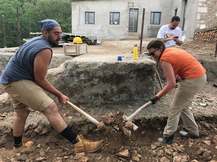 A man and a woman are digging in the dirt with shovels.