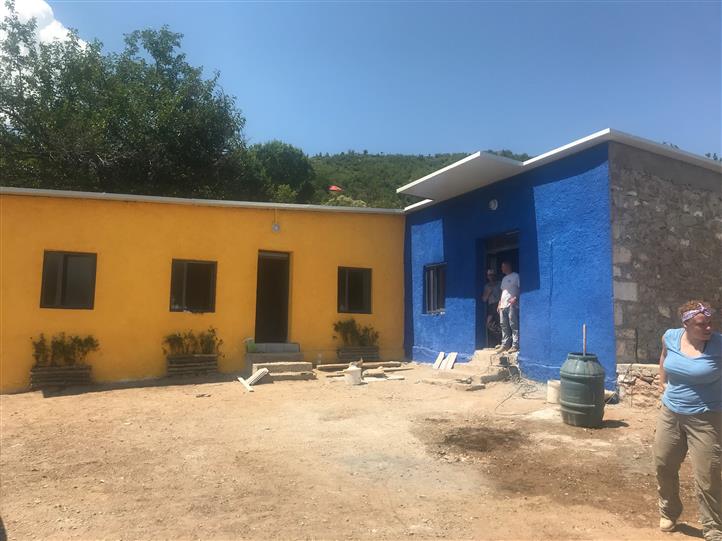 A woman stands in front of a blue and yellow building