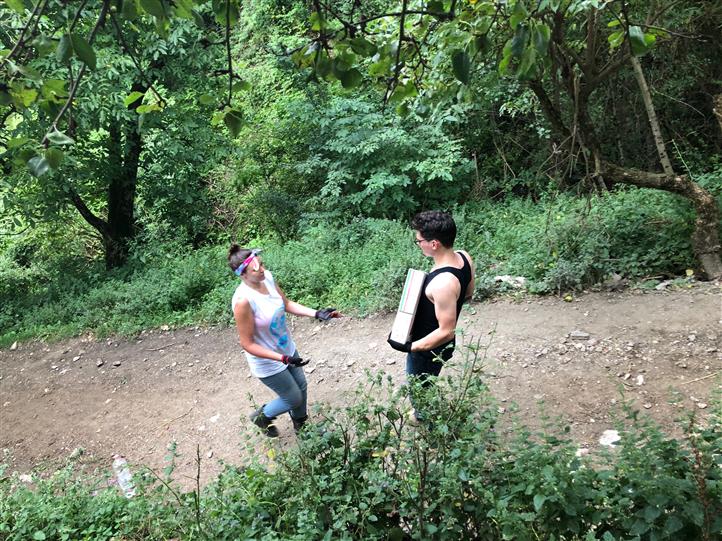 Two people are walking down a dirt path in the woods.